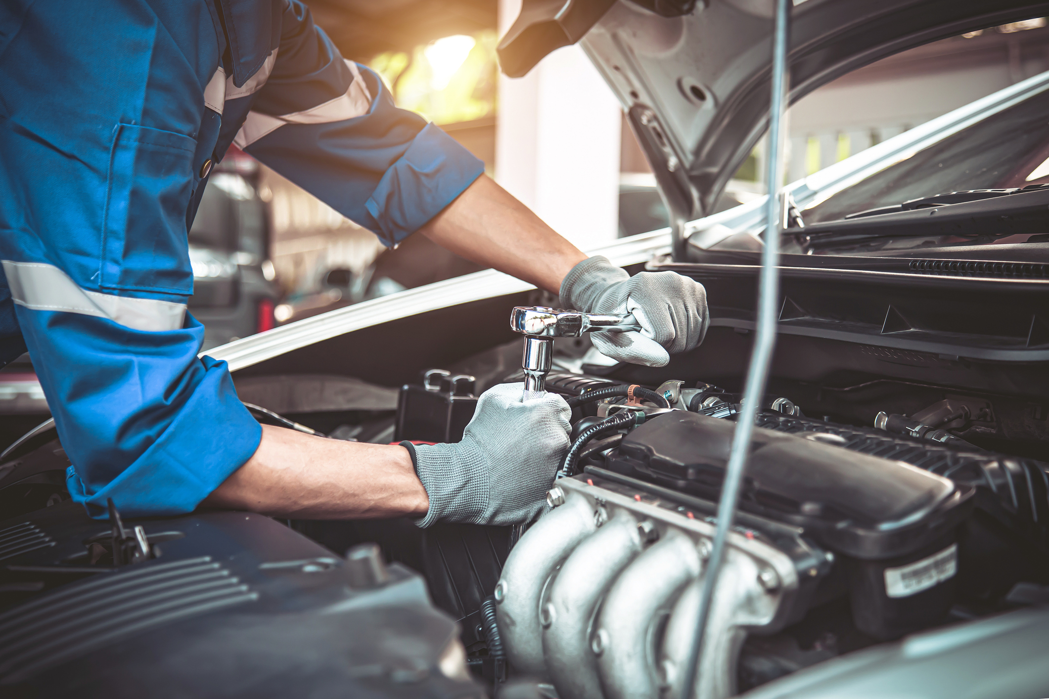 San Diego mechanic performs factory maintenance on a vehicle using a metal tool.