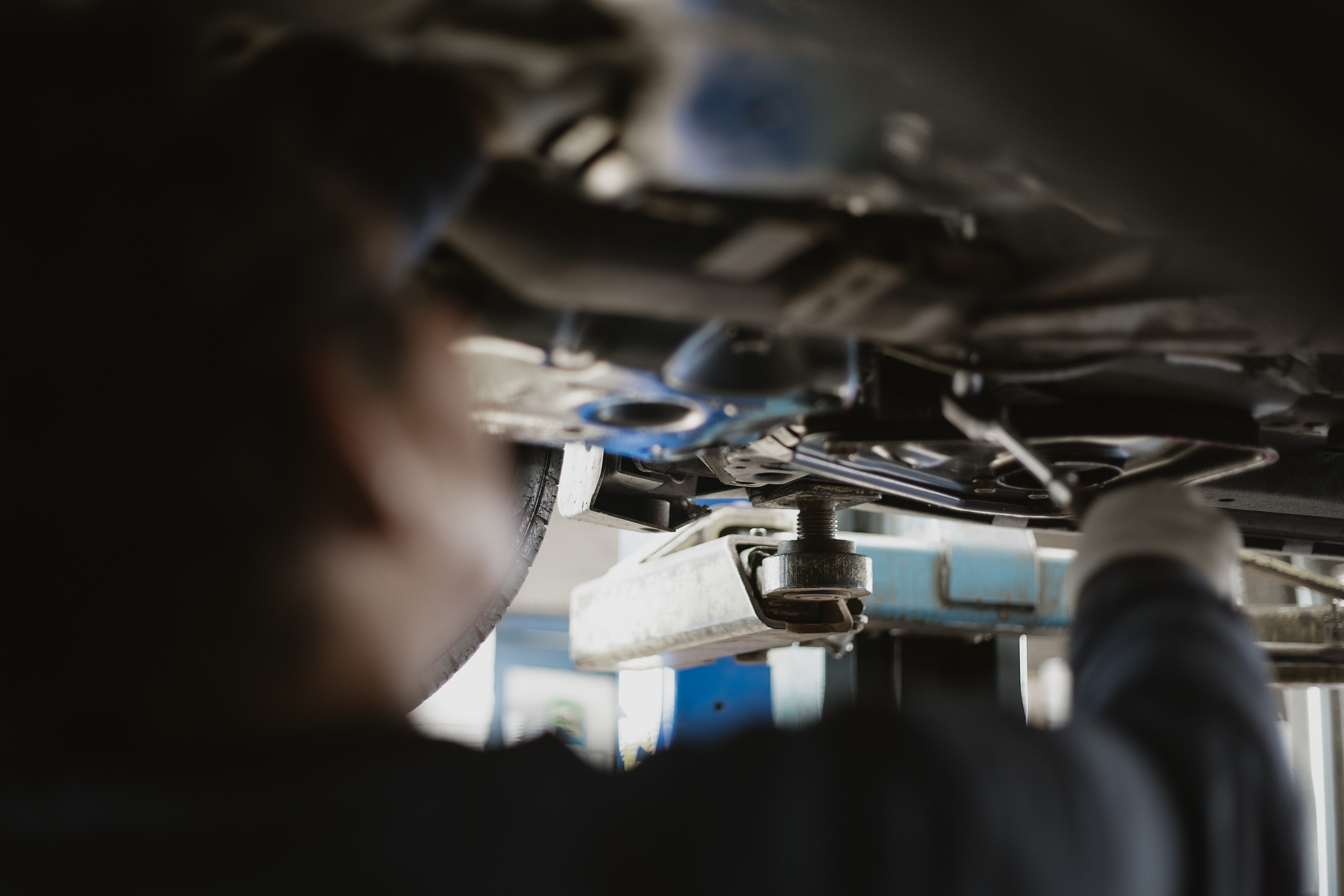 A mechanic who specializes in European vehicles works on the undercarriage of a car.
