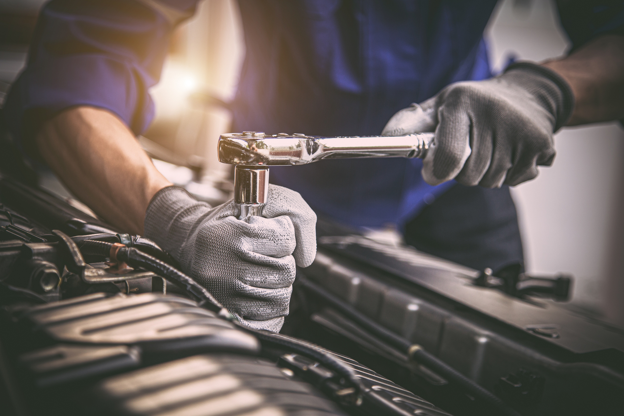 Close-up shot of mechanic repairing European vehicle engine in San Diego, CA.